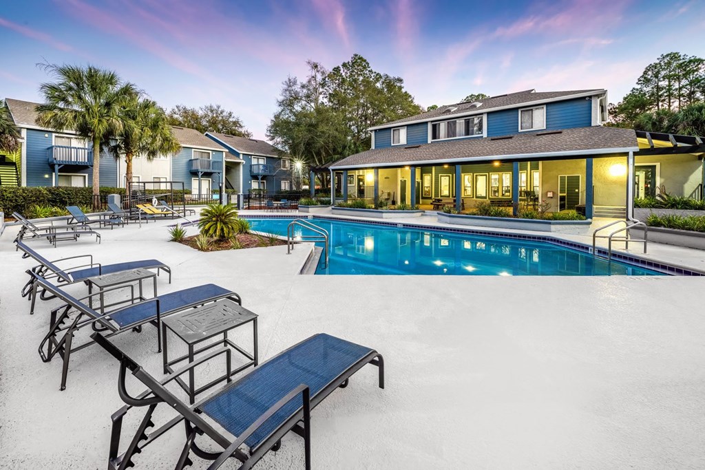 A pool with sun loungers and a building in the background.