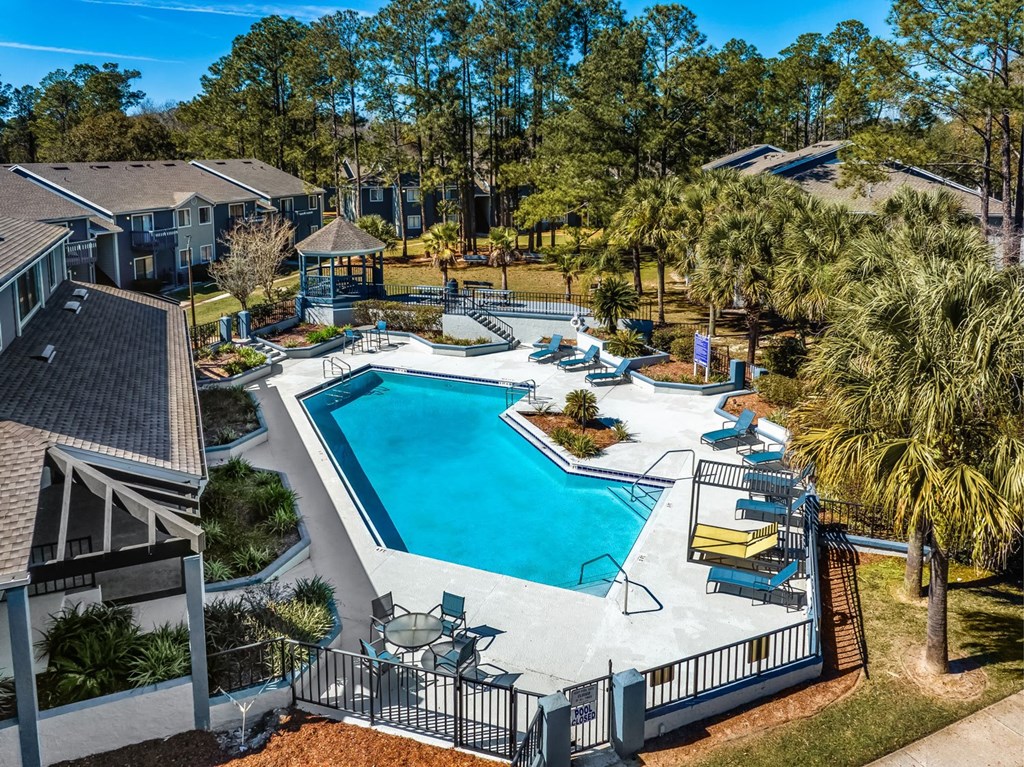 A swimming pool surrounded by a fence and chairs.