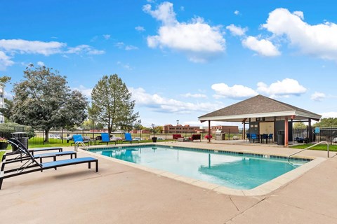 A swimming pool with a bench and a pavilion.
