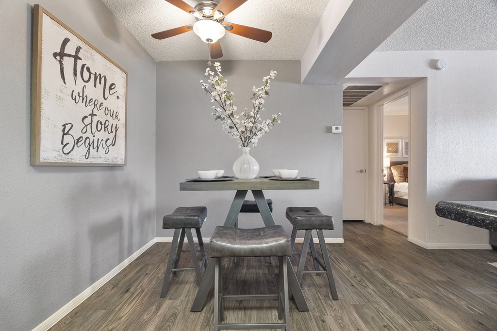 a dining area with a table and chairs and a ceiling fan