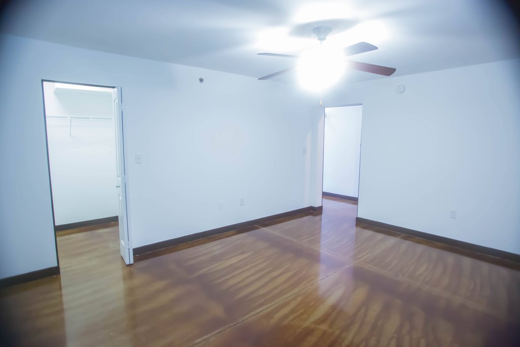 A room with a ceiling fan and wooden floors.