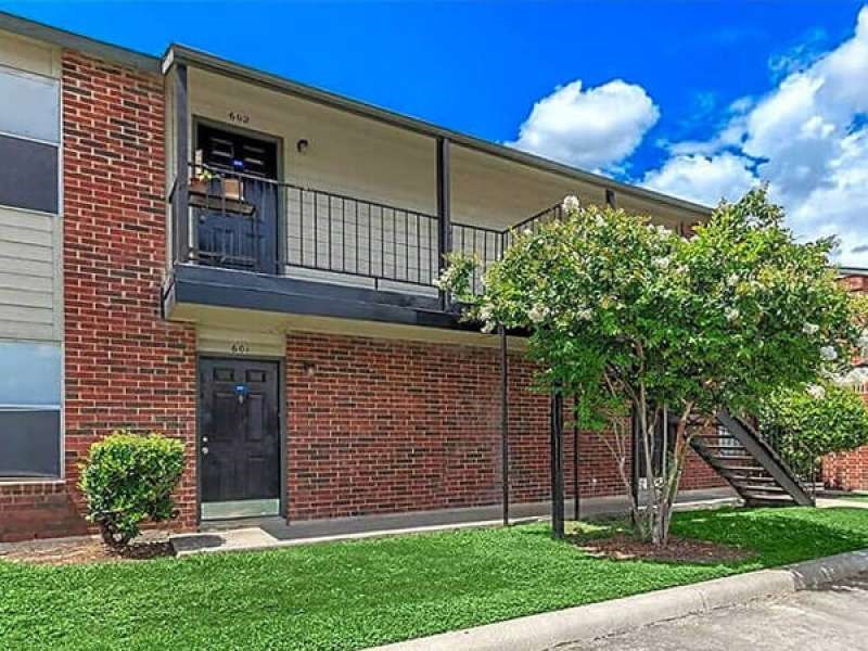 the front of a brick building with a tree in the yard