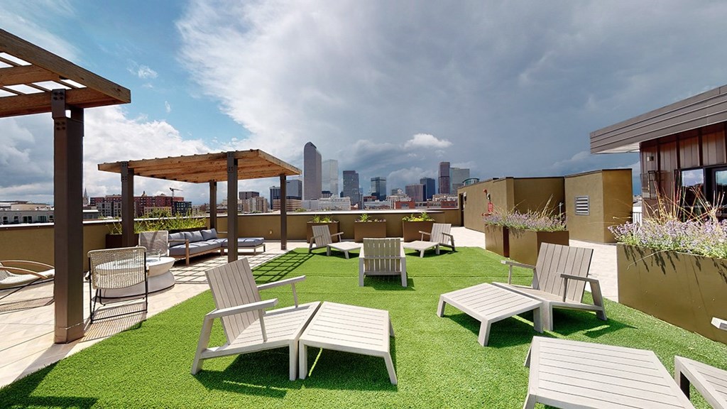 A rooftop patio with white furniture and a view of the city skyline.