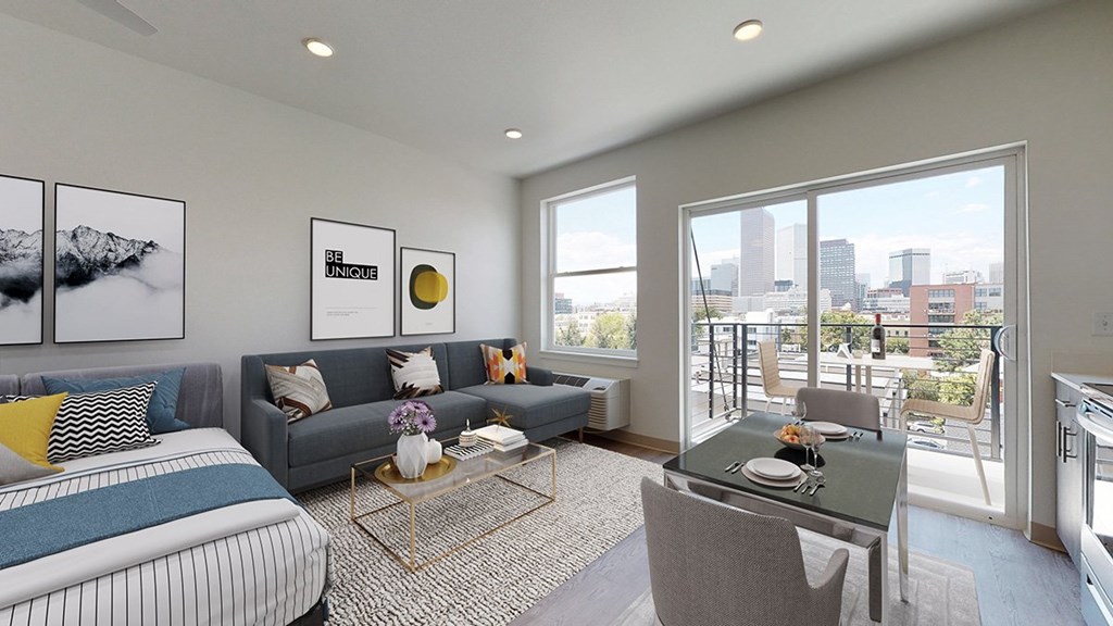 A modern living room with a grey couch, a coffee table, and a large window overlooking the city.