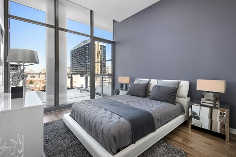 A bedroom with a large bed and a view of the city outside the window.