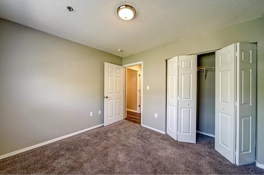 a empty room with closet doors and a door to a hallway
