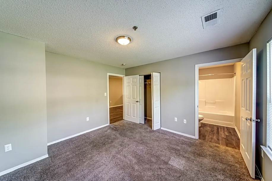 an empty living room with a door to a bathroom and a closet