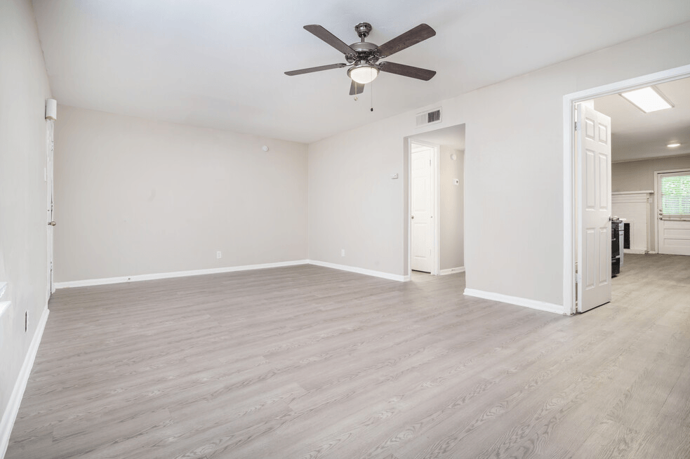 an empty living room with white walls and a ceiling fan