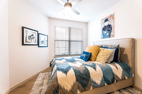 A bedroom with a bed, pillows, and pictures on the wall.