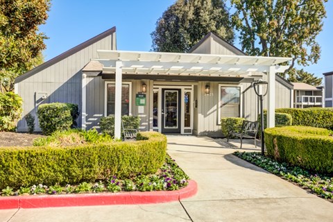 A building with a white canopy and a red border around the bushes.