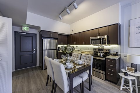 A modern kitchen with a dining table set for two.