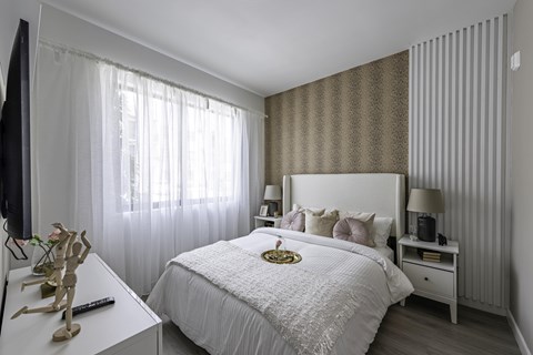 A bedroom with a large bed, a nightstand, and a window with curtains.