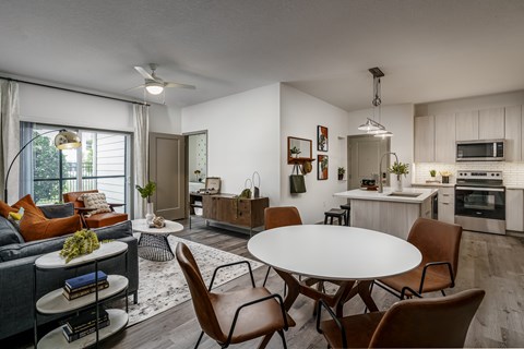 A modern living room with a grey couch, a white coffee table, and a dining table with chairs.