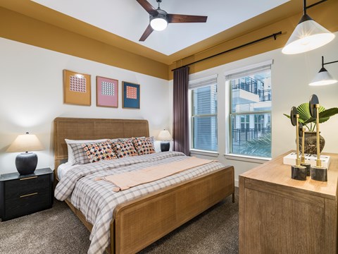 A bedroom with a bed, nightstand, and a ceiling fan.