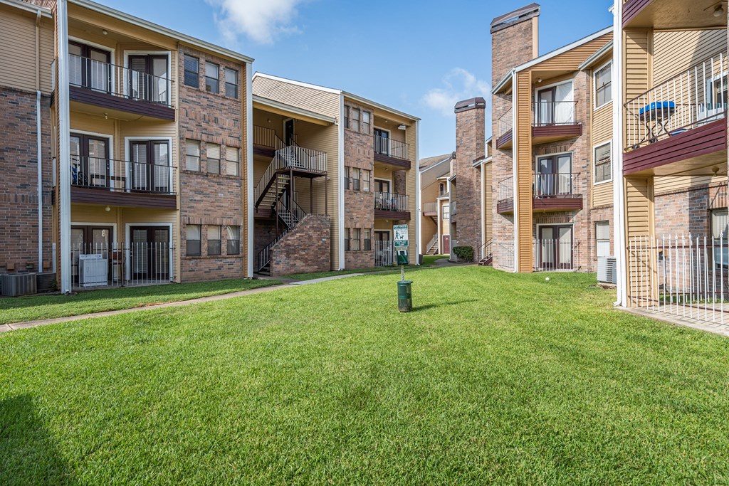 a grassy area at the whispering winds apartments in pearland, tx