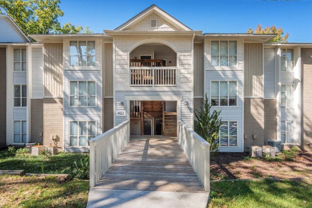 a large white apartment building with a bridge in front of it
