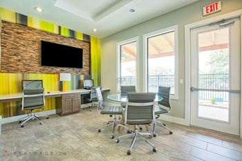 A conference room with a brick wall and a flat screen TV.