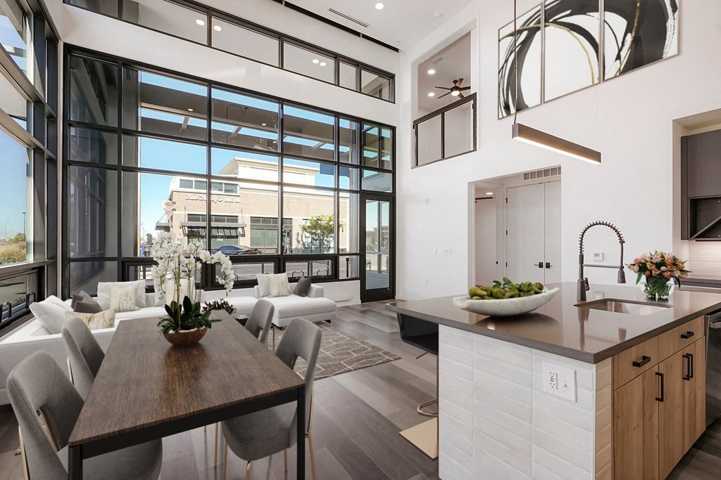 a kitchen and living room with large windows and a table