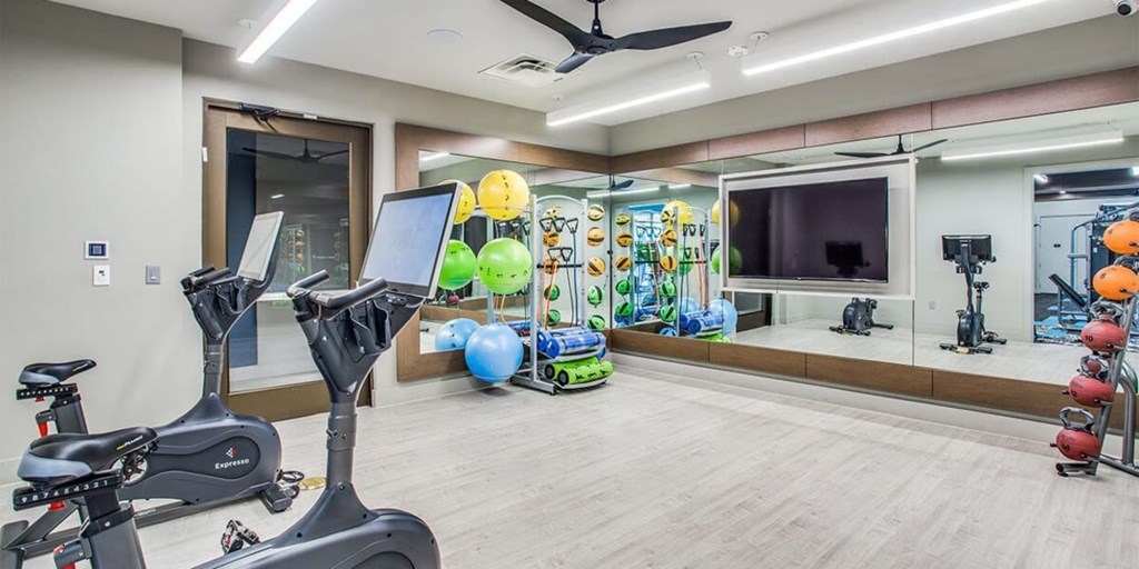 A spacious gym with exercise equipment and a mirrored wall.