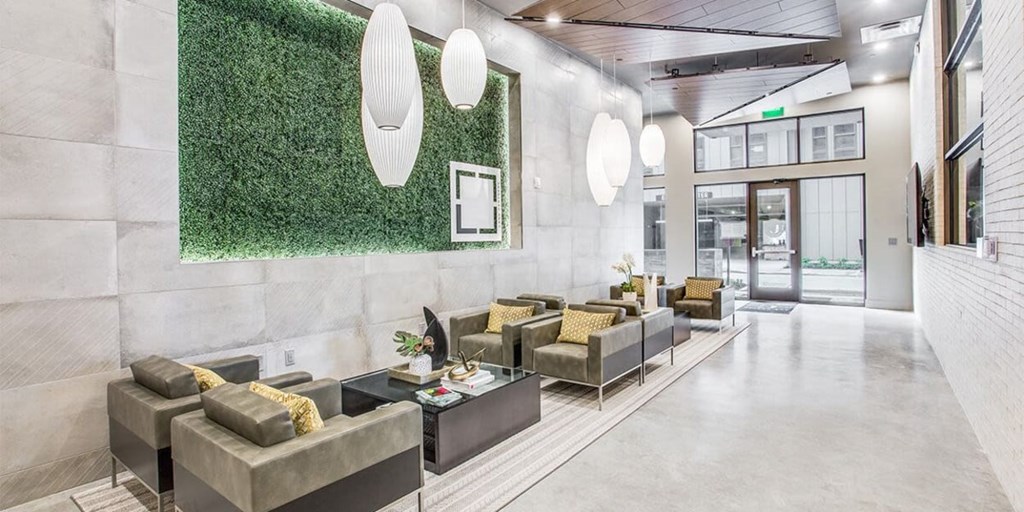 A modern waiting room with grey couches and a green wall.