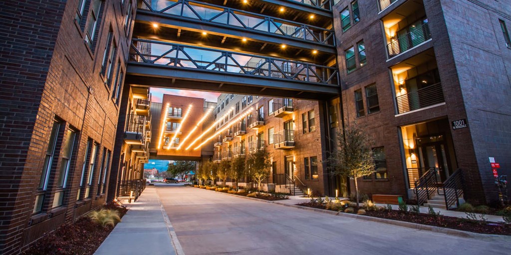 A long, narrow walkway leads to a building with a bridge over it.