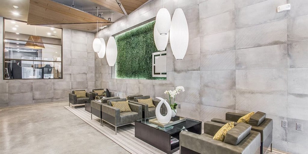 A modern living room with grey couches and a green wall.