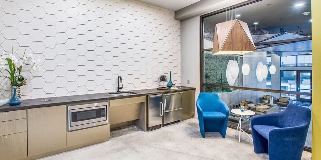 A modern kitchen with a blue chair and a white tiled wall.