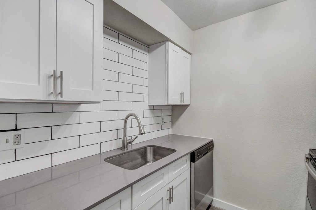 a kitchen with white cabinets and a stainless steel sink