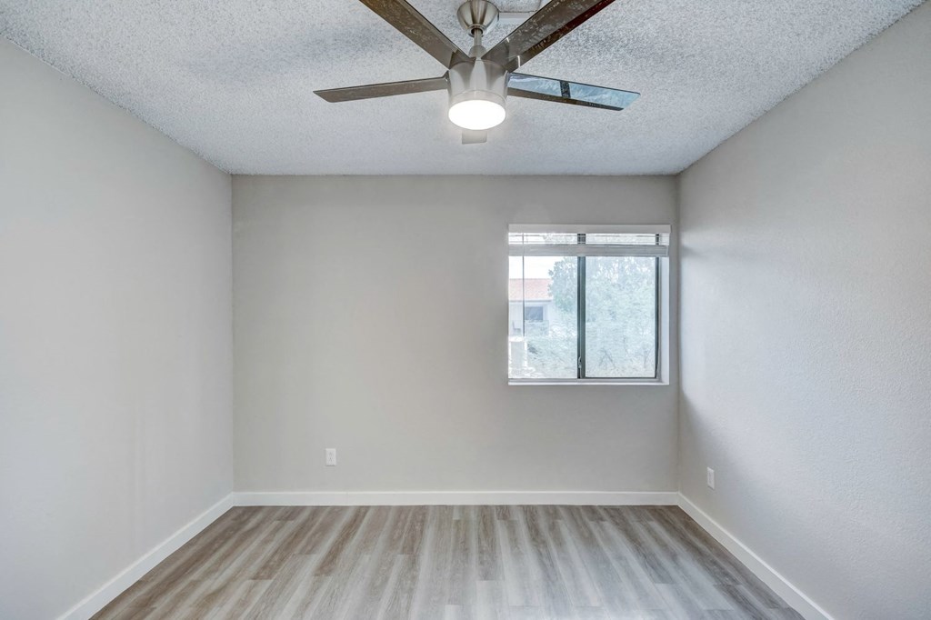 an empty room with a ceiling fan and a window