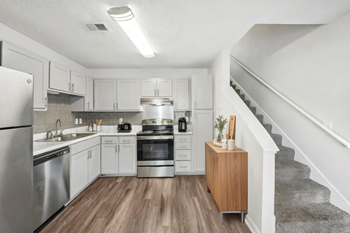 A modern kitchen with stainless steel appliances and wooden floors.