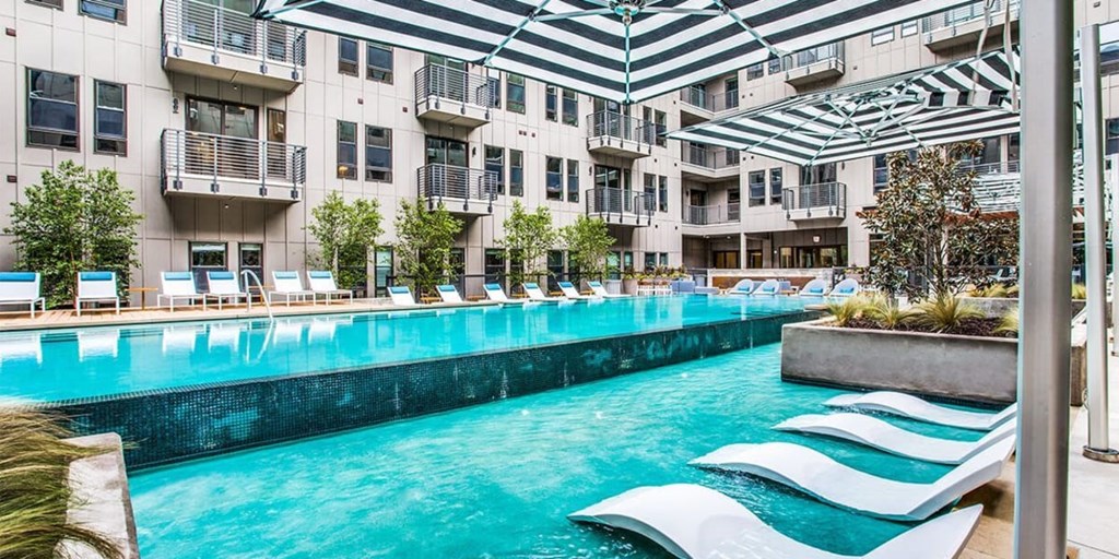 A large indoor pool with lounge chairs and a striped ceiling.