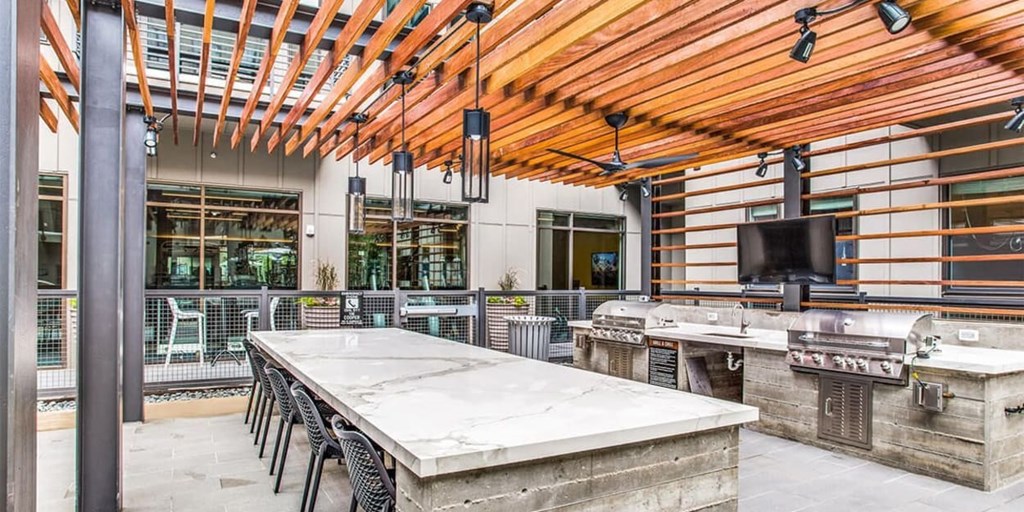 A patio with a table and chairs under a wooden roof.