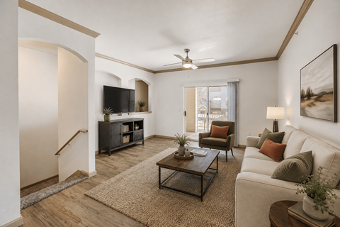 A living room with a white couch, a wooden coffee table, and a flat screen TV.