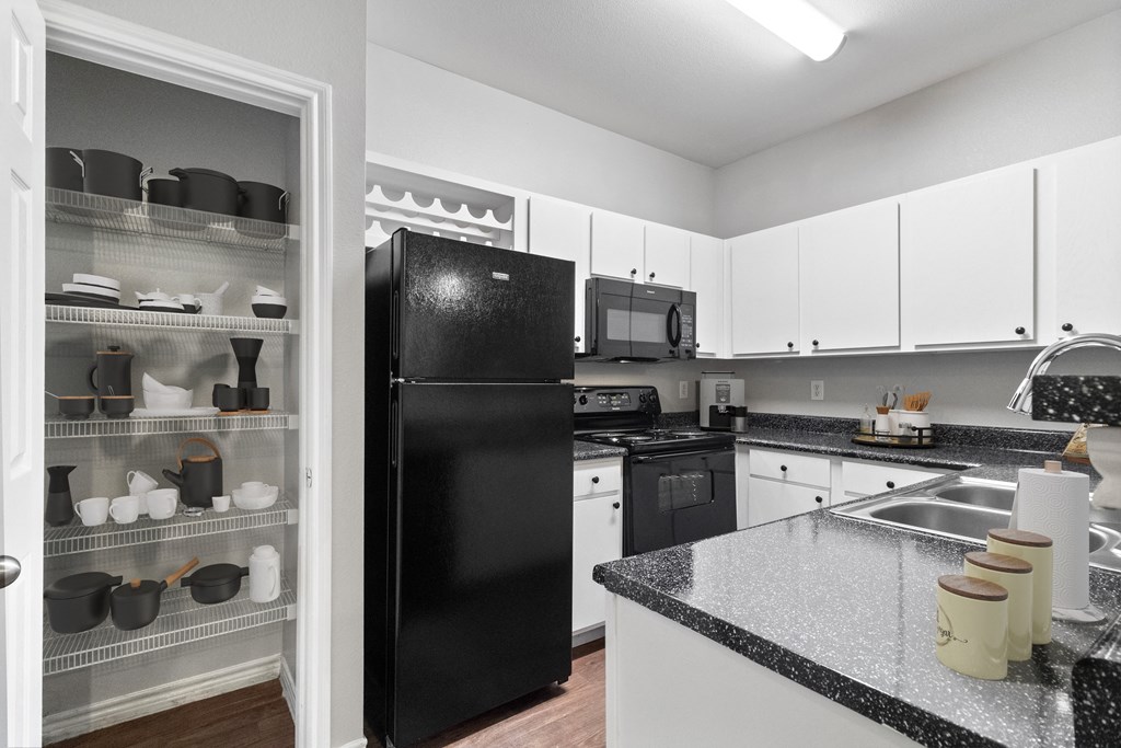 a kitchen with black appliances and white cabinets and granite counter tops