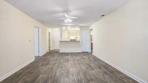 A spacious room with wood flooring and a ceiling fan.