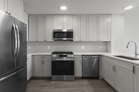 A modern kitchen with a stainless steel refrigerator and white cabinets.