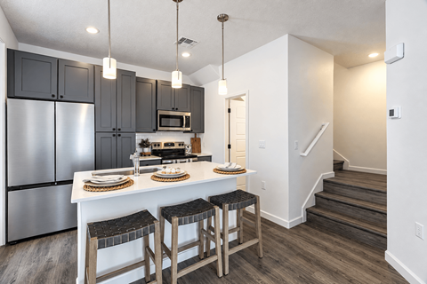 A kitchen with a white table and chairs and a stainless steel refrigerator.