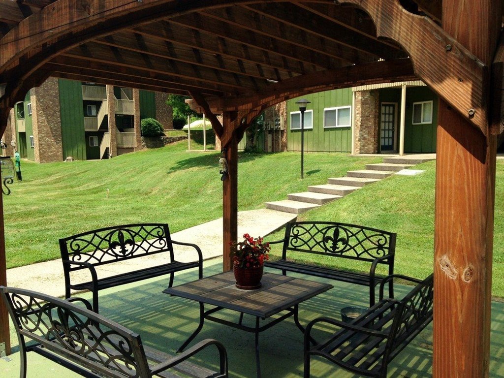 a covered patio with a table and benches