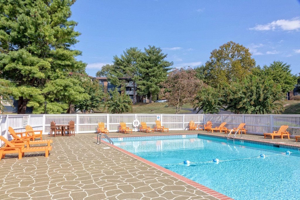 a swimming pool with orange chairs around it