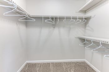 Empty white closet with clothes hangers.