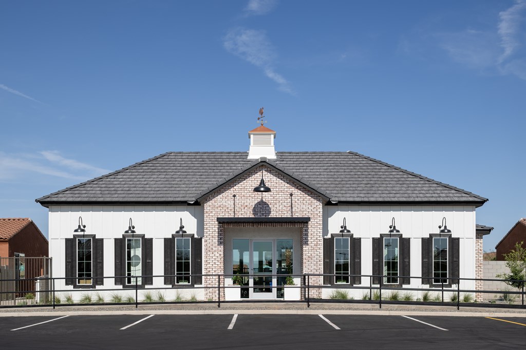 A white building with black shutters and a black roof with a white cupola.