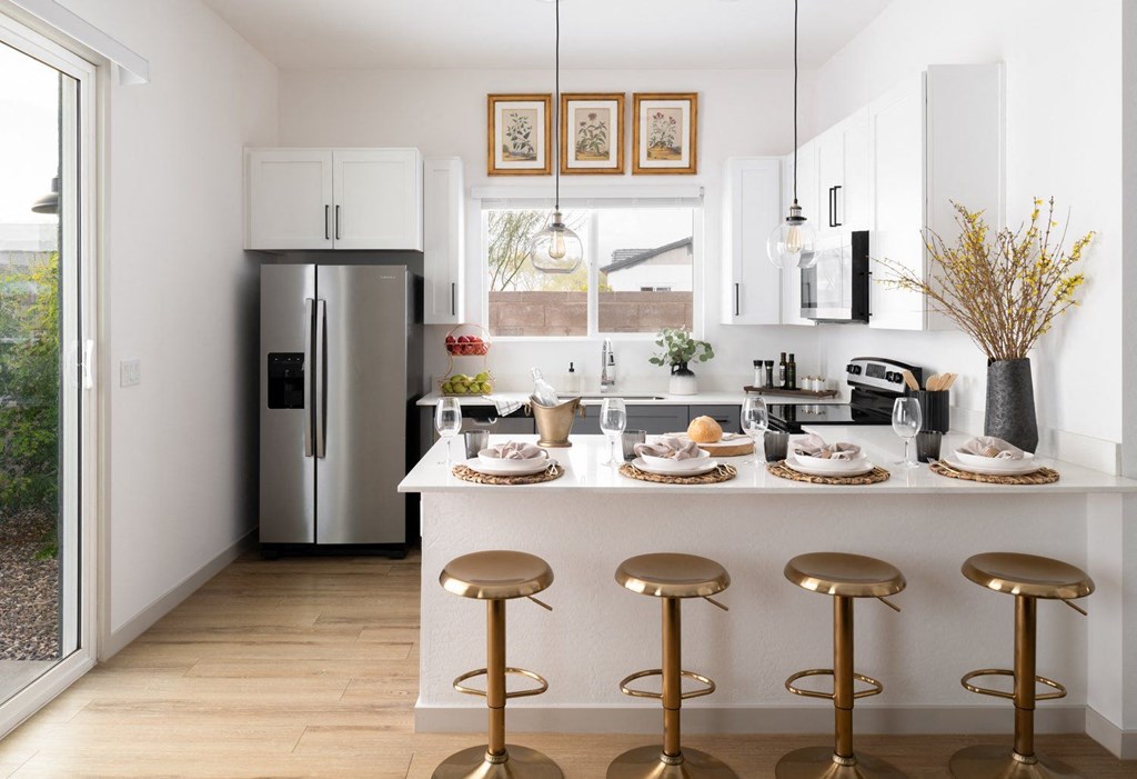 A kitchen with a white counter and gold stools.