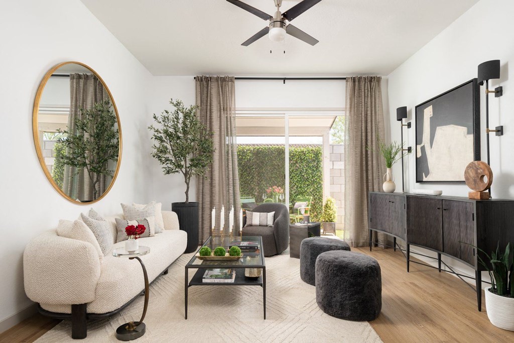 A living room with a white couch, a coffee table, and a large mirror on the wall.