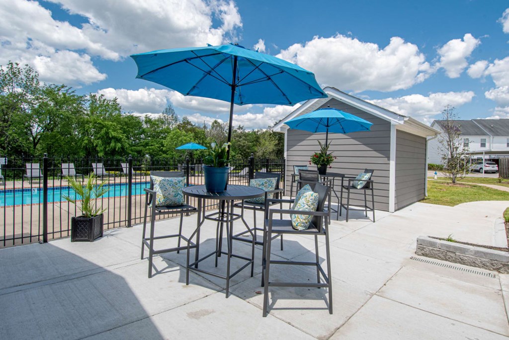 A blue umbrella is on a table outside a house.
