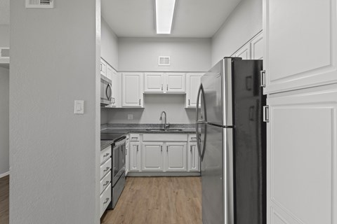 A kitchen with white cabinets and a black refrigerator.