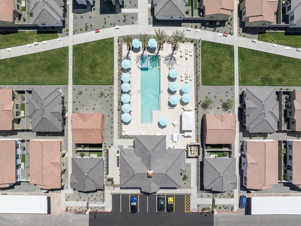 A bird's eye view of a residential area with a pool and apartment buildings.