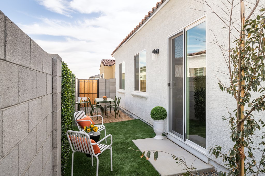 A patio with a table and chairs is surrounded by a wall and a tree.