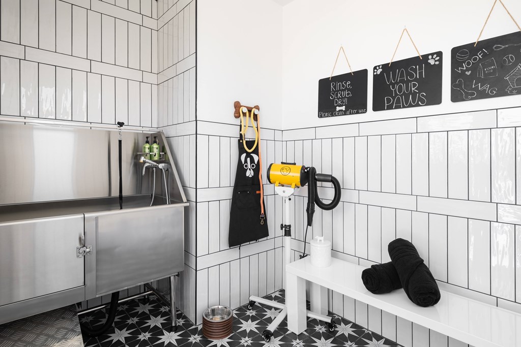A bathroom with a white tiled wall and a black and white floor.