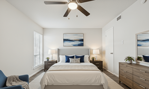 A bedroom with a bed, a chair, and a ceiling fan.