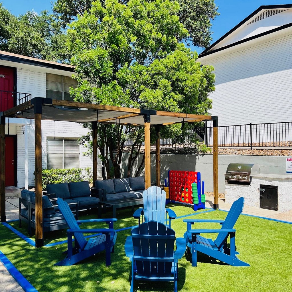 a backyard patio with blue chairs and a canopy